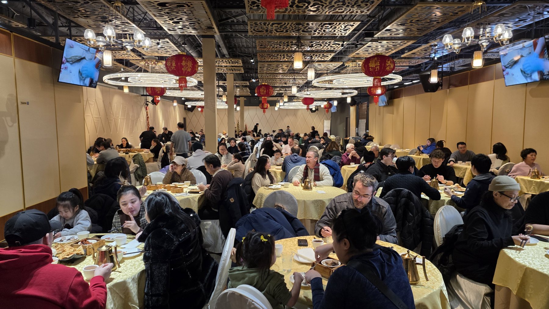 La salle comble au service du dim sum, familles autour des tables rondes