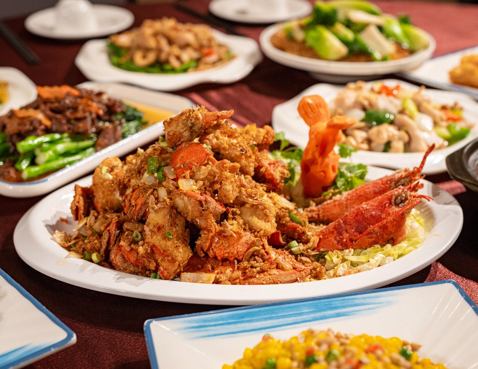 Homard frit à l'ail au centre d'une table de plats du wok à partager